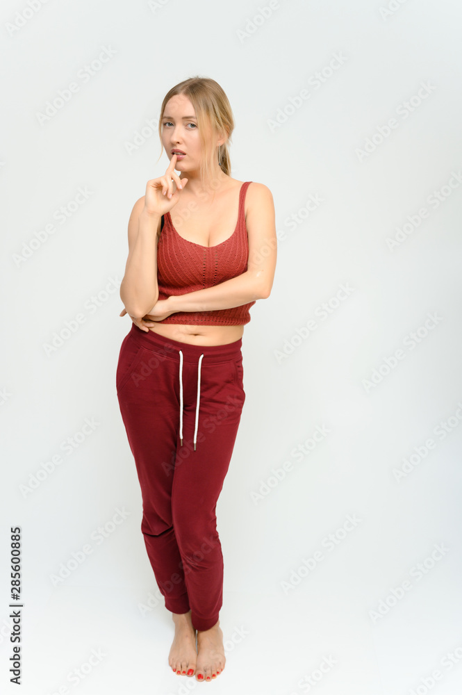 Full length studio portrait of a pretty young happy blonde woman in a tracksuit on a white background. He smiles, talks, shows with his hands, moves, shows emotions. Full length studio portrait of a pretty young happy blonde woman in a tracksuit on a white background. He smiles, talks, shows with his hands, moves, shows emotions.