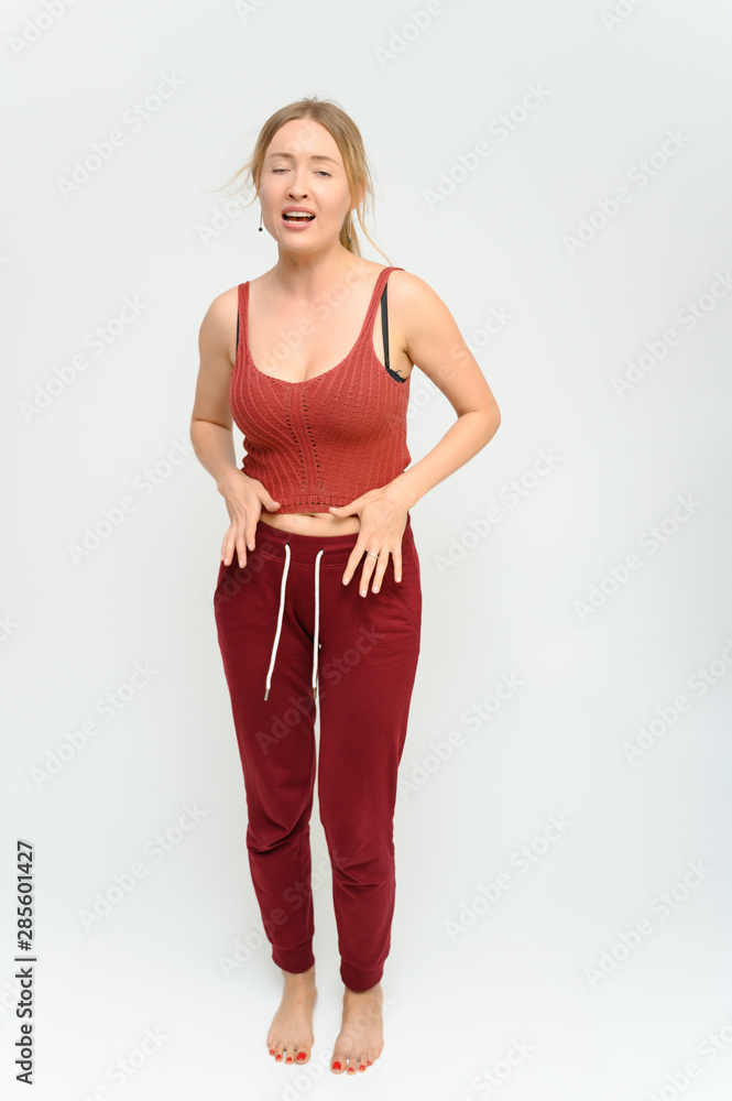 Full length studio portrait of a pretty young happy blonde woman in a tracksuit on a white background. He smiles, talks, shows with his hands, moves, shows emotions. Full length studio portrait of a pretty young happy blonde woman in a tracksuit on a white background. He smiles, talks, shows with his hands, moves, shows emotions.