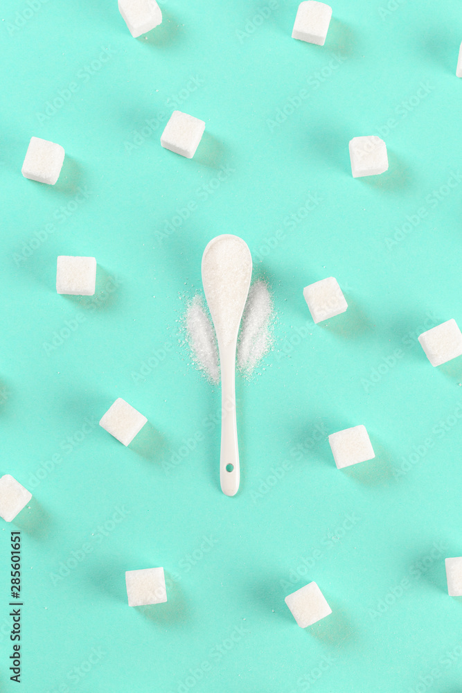 .background of sugar cubes and sugar in spoon. White sugar on turquoise background. Sugar with copy space. .background of sugar cubes and sugar in spoon. White sugar on turquoise background. Sugar with copy space.