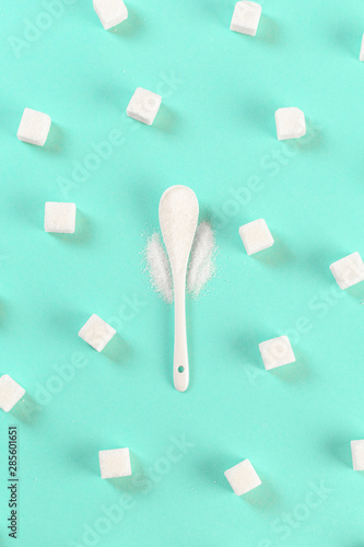 .background of sugar cubes and sugar in spoon. White sugar on turquoise background. Sugar with copy space.