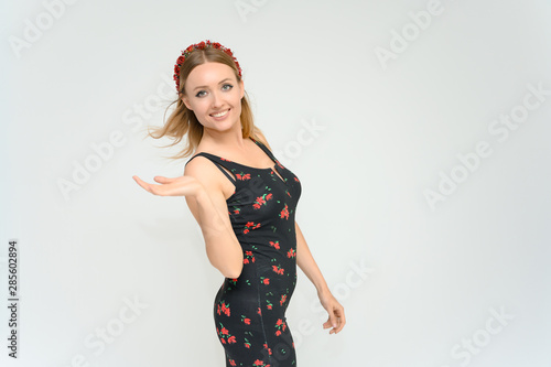 Studio portrait portrait of a pretty young happy blonde woman in a beautiful dress on a white background. He smiles, talks, shows with his hands, moves, shows emotions.