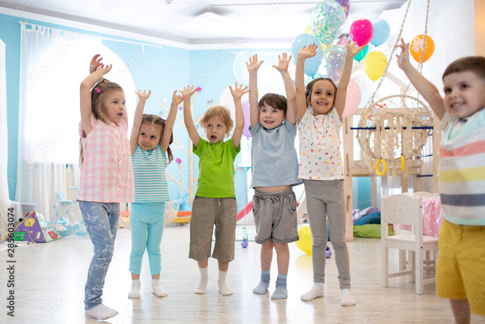 Fototapeta premium Happy kids with their hands up at daycare or children club