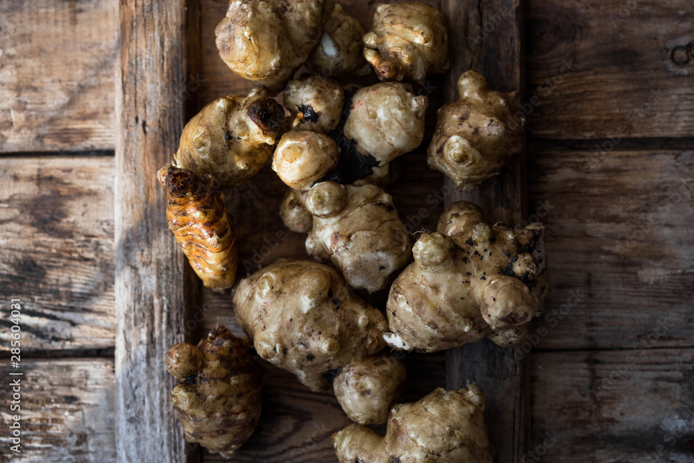 Whole ans sliced Jerusalem artichokes on a cutting board Whole ans sliced Jerusalem artichokes on a cutting board