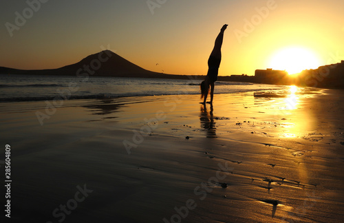 Girl doing handstand on beach at sunset in Tenerife, Spain