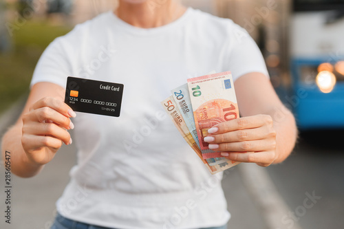 Girl's holding euro bills and credit card. Online shopping traveling around the wolrd