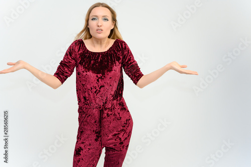 Studio knee-length portrait of a pretty beautiful young happy blonde woman on a white background in red overalls. Smiling, talking, showing emotions. photo