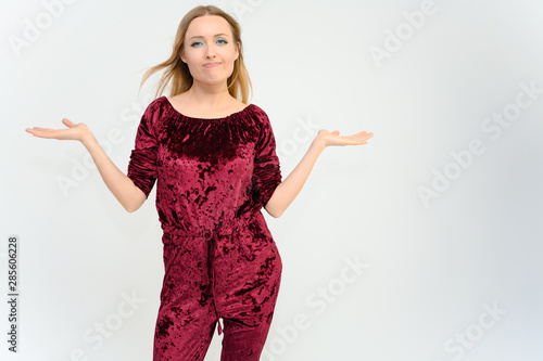 Studio knee-length portrait of a pretty beautiful young happy blonde woman on a white background in red overalls. Smiling, talking, showing emotions. photo