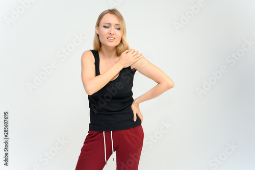 Studio knee-length portrait of a pretty beautiful young happy blonde woman on a white background in a black t-shirt and red trousers. Smiling, talking, showing emotions. © Вячеслав Чичаев