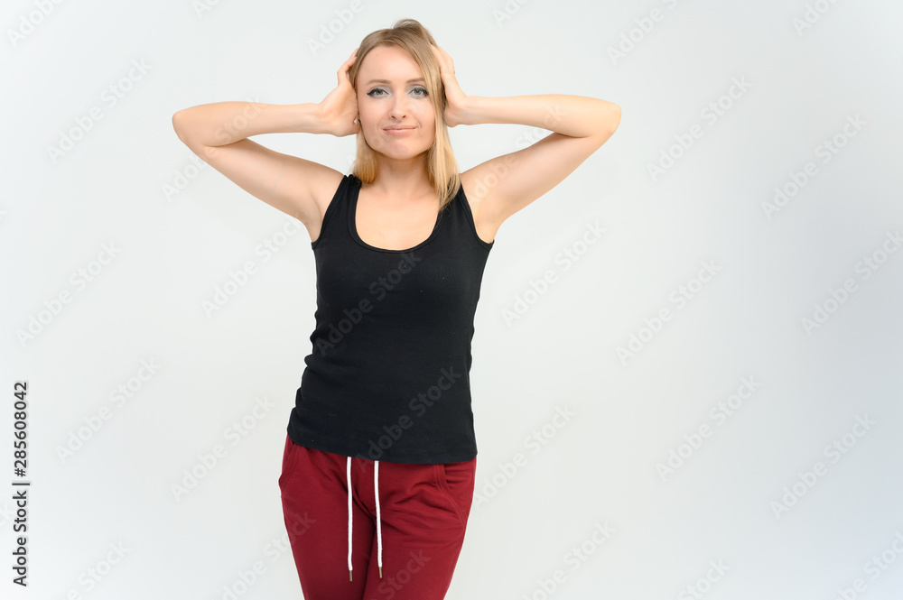 Studio knee-length portrait of a pretty beautiful young happy blonde woman on a white background in a black t-shirt and red trousers. Smiling, talking, showing emotions. Studio knee-length portrait of a pretty beautiful young happy blonde woman on a white background in a black t-shirt and red trousers. Smiling, talking, showing emotions.