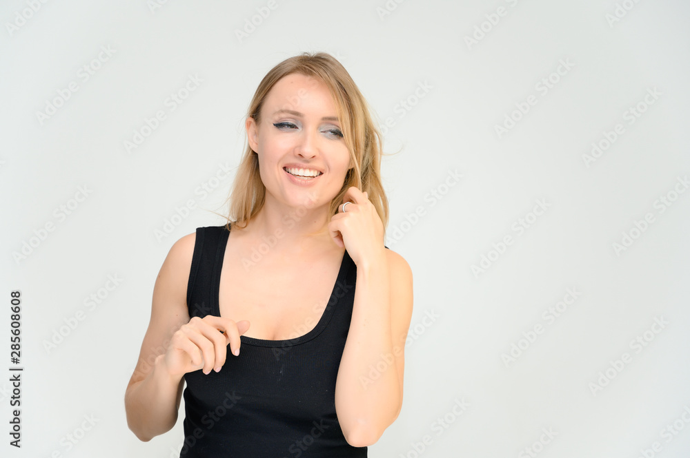 Studio waist-length photo portrait of a pretty beautiful young happy blonde woman on a white background in a black t-shirt. Smiling, talking, showing emotions. Studio waist-length photo portrait of a pretty beautiful young happy blonde woman on a white background in a black t-shirt. Smiling, talking, showing emotions.