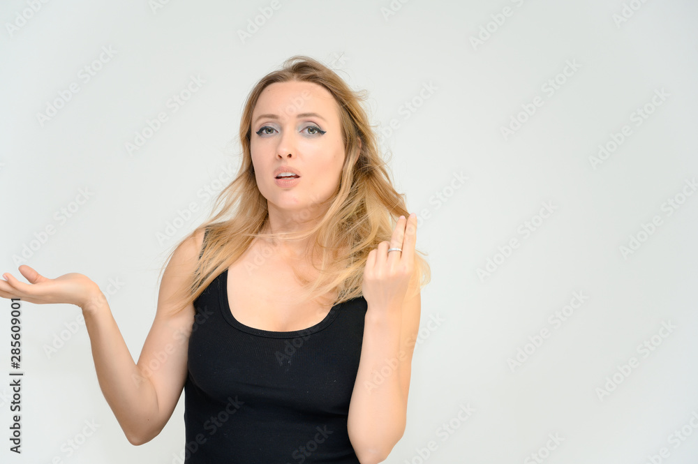 Studio waist-length photo portrait of a pretty beautiful young happy blonde woman on a white background in a black t-shirt. Smiling, talking, showing emotions. Studio waist-length photo portrait of a pretty beautiful young happy blonde woman on a white background in a black t-shirt. Smiling, talking, showing emotions.