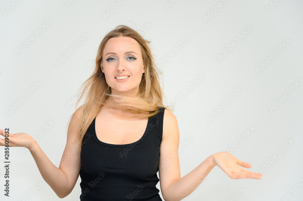 Studio waist-length photo portrait of a pretty beautiful young happy blonde woman on a white background in a black t-shirt. Smiling, talking, showing emotions. Studio waist-length photo portrait of a pretty beautiful young happy blonde woman on a white background in a black t-shirt. Smiling, talking, showing emotions.