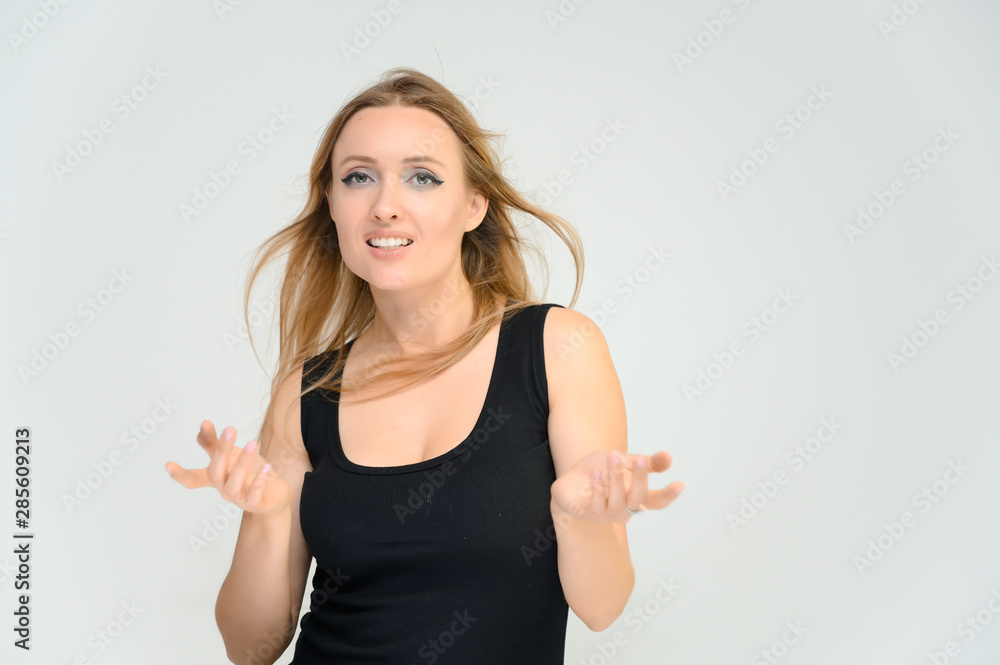 Studio waist-length photo portrait of a pretty beautiful young happy blonde woman on a white background in a black t-shirt. Smiling, talking, showing emotions. Studio waist-length photo portrait of a pretty beautiful young happy blonde woman on a white background in a black t-shirt. Smiling, talking, showing emotions.