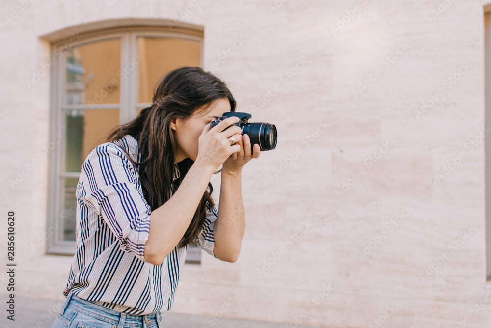 Young woman with camera taking photos in vacation