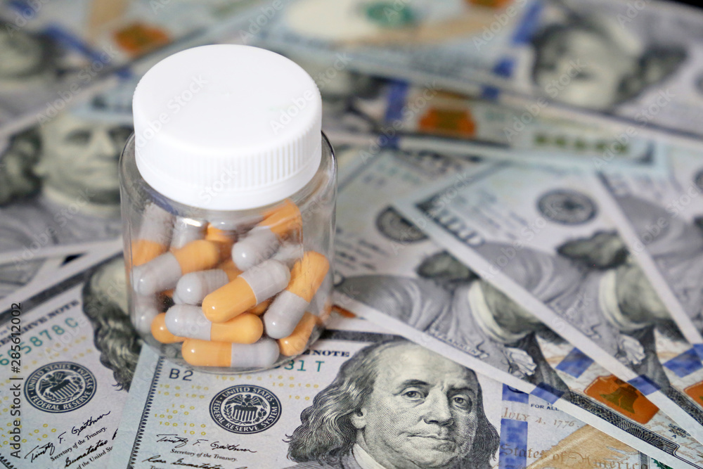 Pills in a bottle on US dollars bills. Concept of health care, medication in capsules, pharmaceutical business, drug prices, pharmacy, medicine and economics Pills in a bottle on US dollars bills. Concept of health care, medication in capsules, pharmaceutical business, drug prices, pharmacy, medicine and economics