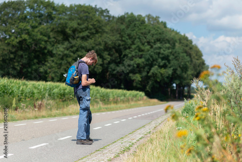Young man with backpack on country road in summer. © ysbrandcosijn