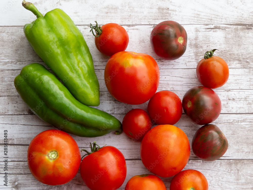 Green peppers and tomatoes of different shapes and sizes on wooden surface Green peppers and tomatoes of different shapes and sizes on wooden surface