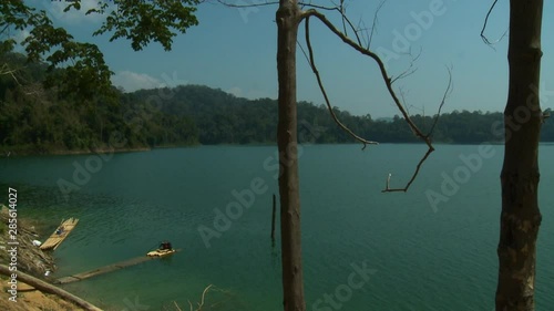 Wide low-angle still shot view of calm Temenggor Lake, and tropical rain forest Island landscapes from a remote aboriginal village, Orang Asli Village, Cameron Hills, Kuala Lumpur, Malaysia photo