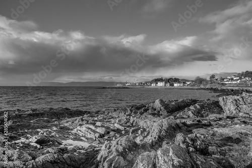 A Black & White image of Largs Looking over Lichen Covered Rocks to the Town in the Far Distance photo