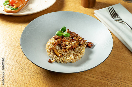 Close up view on delicious boiled whole grain oatmeal with small forest mushrooms. tasty vegetarian food. Healthy and balanced meal for breakfast. wooden background. selective focus.