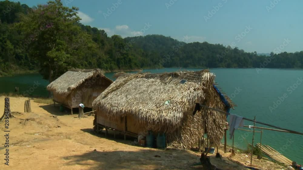 Wide low-angle still shot of Orang Asli Village palm thatched roof houses close to Temenggor Lake, Cameron Highlands, Malaysia Wide low-angle still shot of Orang Asli Village palm thatched roof houses close to Temenggor Lake, Cameron Highlands, Malaysia