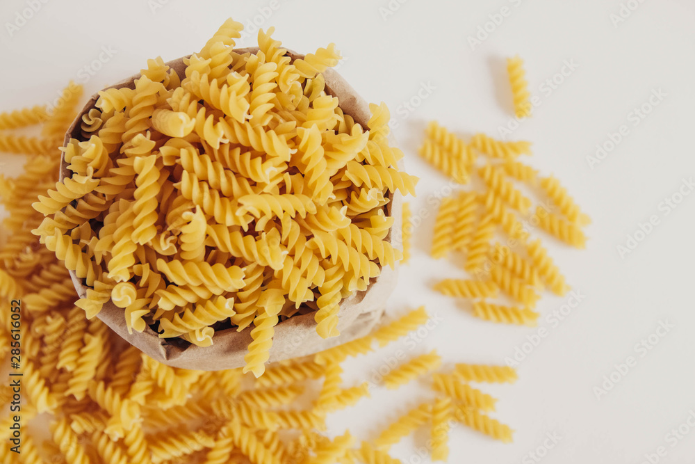 Spiral pasta in a paper bag on a white background. Top view. Copy, empty space for text Spiral pasta in a paper bag on a white background. Top view. Copy, empty space for text