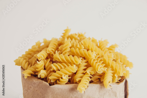 Spiral pasta in a paper bag on a white background. Copy  empty space for text