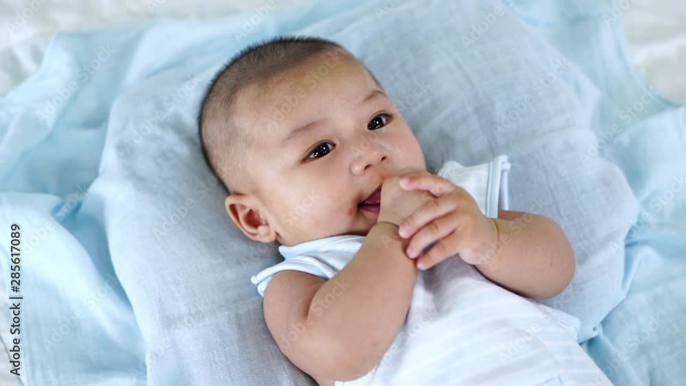 slow-motion of little baby with finger in mouth on a bed slow-motion of little baby with finger in mouth on a bed
