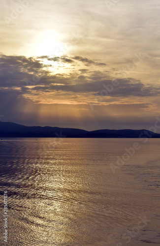 Greece, the Aegean sea. A view from a ferry sailing at sunset. The sunset over the distant isle of Kythnos. An atmospheric sky. Natural beauty. Nature, open air and calmness. © John