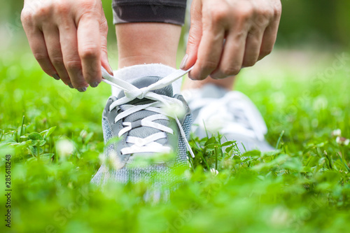 Woman runner tying shoelace on nature trail