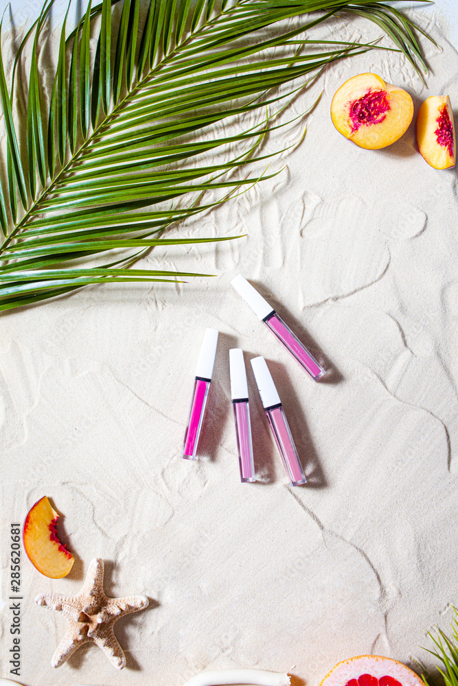 Wonderful beach. Lipstick, lip gloss, lip balm lie on the sand, surrounded by juicy fruits, starfish, and palm leaves. Wonderful beach. Lipstick, lip gloss, lip balm lie on the sand, surrounded by juicy fruits, starfish, and palm leaves.