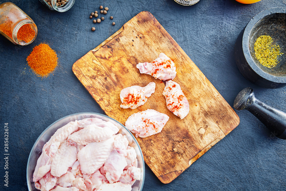 Raw chicken wings with spices on a wooden cutting board Raw chicken wings with spices on a wooden cutting board