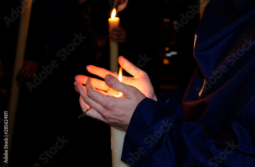 Photos Closeup of the hands of a nazarene penitent during a nocturnal procession holding his candle