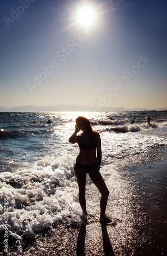 woman standing on a sunset in ocean waves