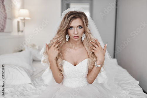 The bride's fees at the hotel. A beautiful blonde is standing at the window in a wedding dress.