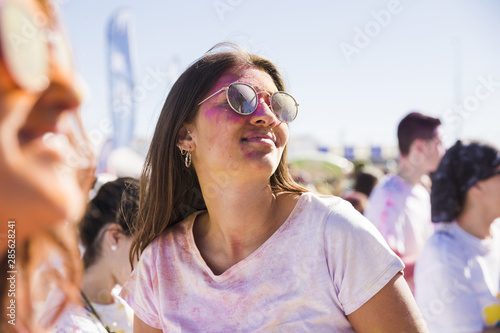 Close-up of woman wearing sunglasses playing with holi color © Freepik