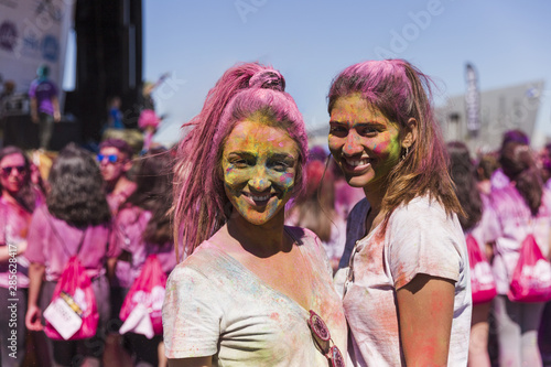 Smiling portrait of a young women with holi powder on their face looking at camera