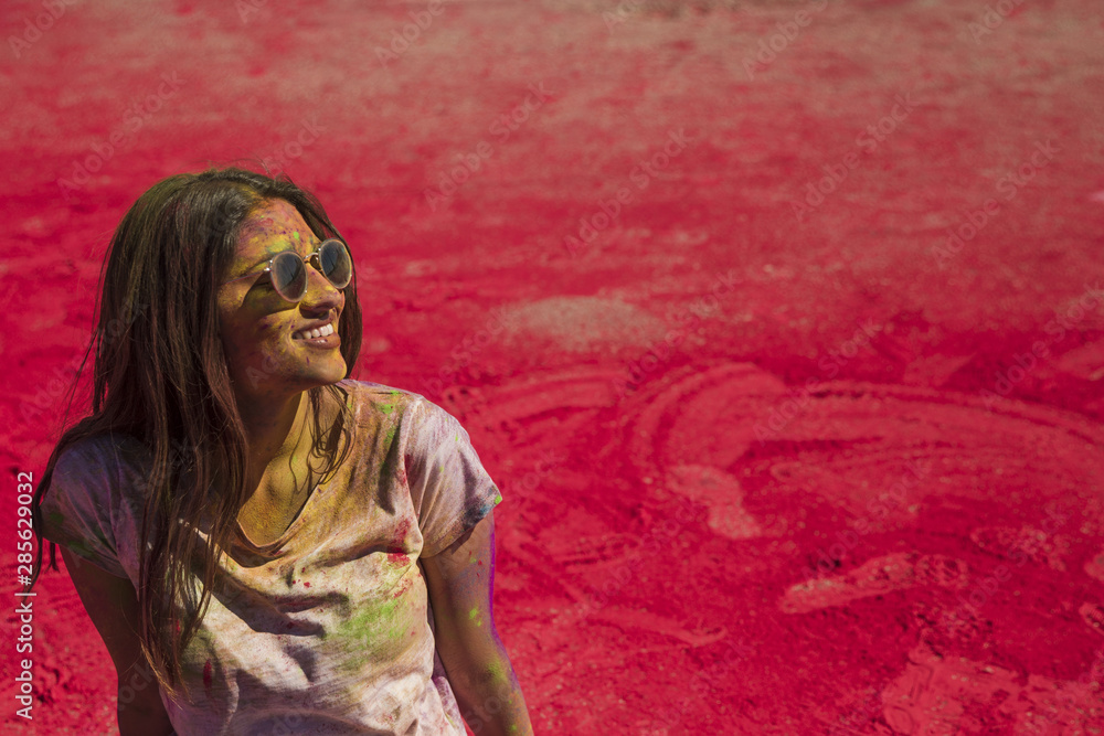 Portrait of a smiling young woman wearing sunglasses messing in holi color Portrait of a smiling young woman wearing sunglasses messing in holi color