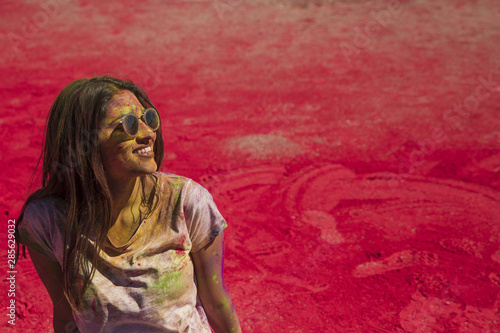 Portrait of a smiling young woman wearing sunglasses messing in holi color