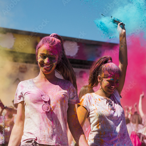 Two young women covered with holi color dancing in the holi festival