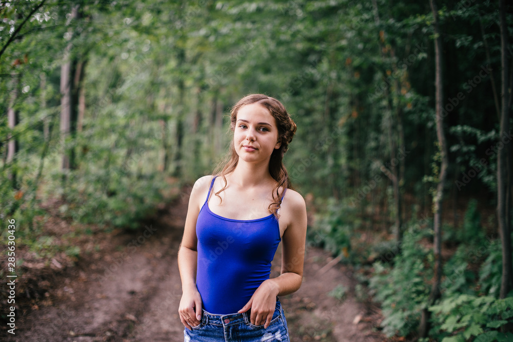 Beautiful girl in short shorts and a blue T-shirt in the woods Beautiful girl in short shorts and a blue T-shirt in the woods