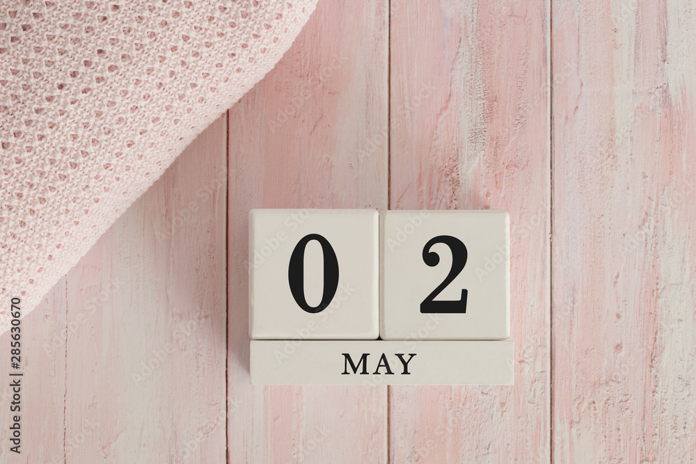 2 May Date on Cubes. Date on painted pink wood, next to baby blanket. Theme of baby due dates and birth dates. 2 May Date on Cubes. Date on painted pink wood, next to baby blanket. Theme of baby due dates and birth dates.