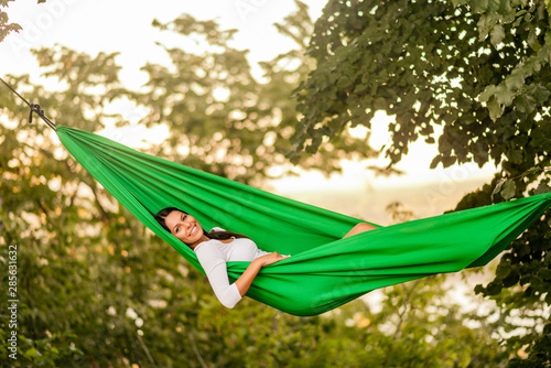 Portrait of a young woman lying in a hammock in a garden. © bnenin
