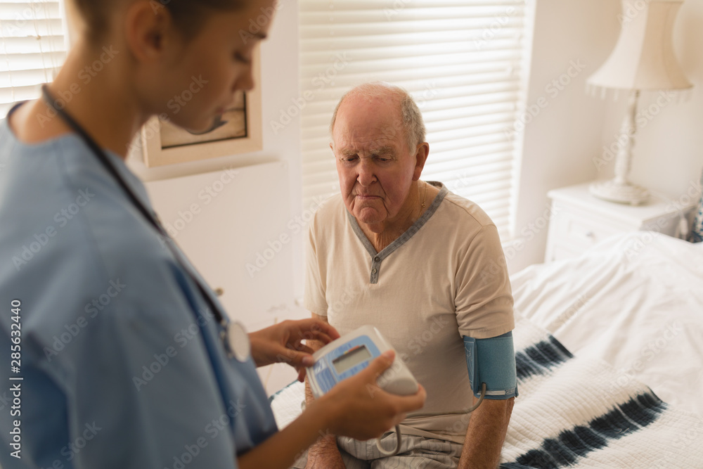 Fototapeta premium Female doctor checking blood pressure of senior man
