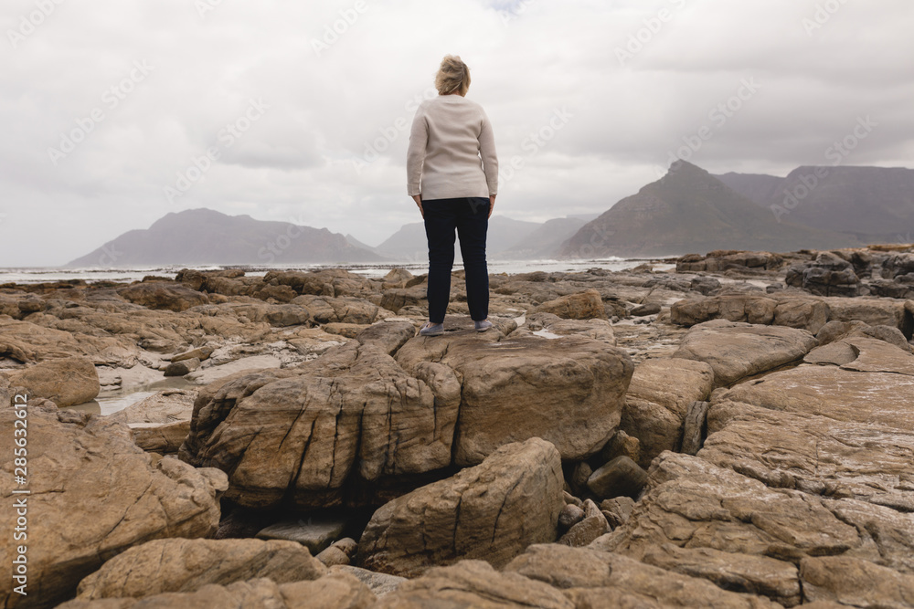 Happy senior woman standing on the rock at beach