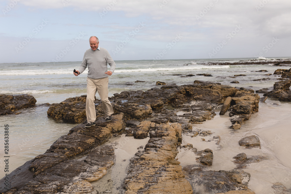 Senior man walking on the rock at beach