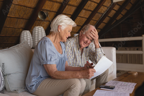 Senior couple discussing over medical bills in living room photo