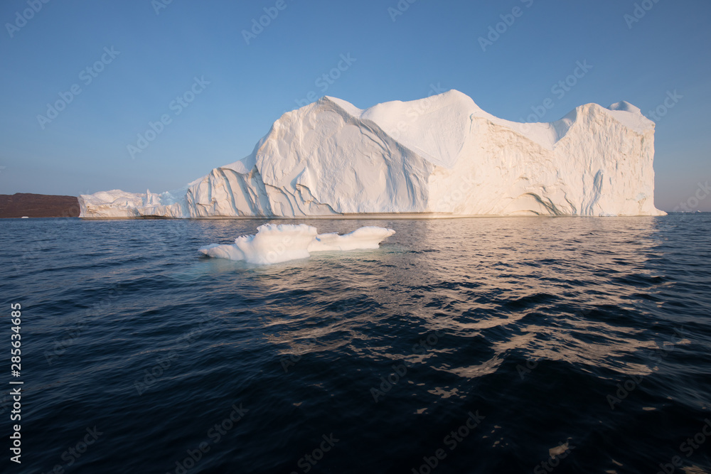 Photogenic and intricate iceberg under an interesting and blue sky during sunset. Effect of global warming in nature. Conceptual image of melting glacier in deep blue water in Antarctica or Greenland Photogenic and intricate iceberg under an interesting and blue sky during sunset. Effect of global warming in nature. Conceptual image of melting glacier in deep blue water in Antarctica or Greenland