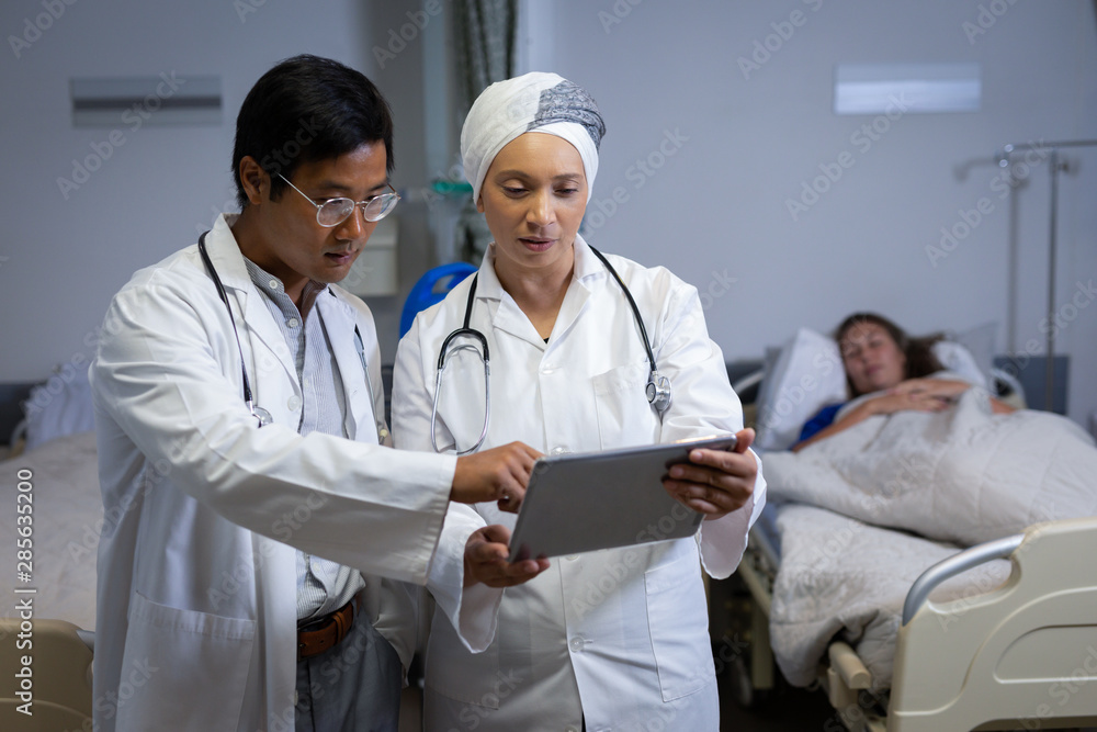Doctors discussing over digital tablet in clinic at hospital