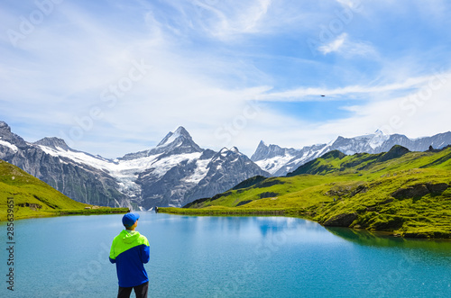 Young man operating the flying drone over beautiful Bachalpsee in the Swiss Alps. Drone cameras are used for aerial photography and footage. Switzerland landscape. Drone noise